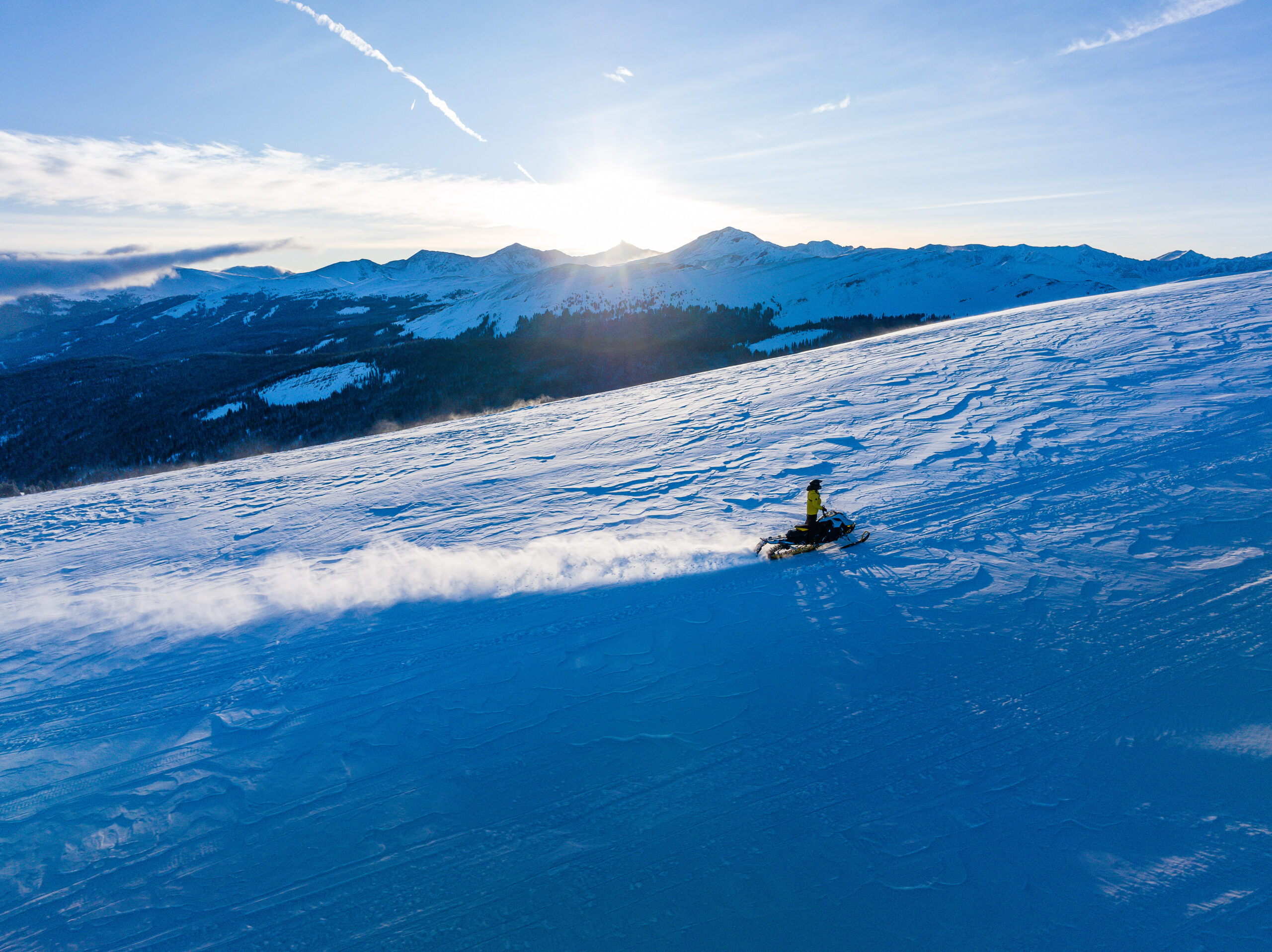 Snowmobiler riding through Colorado backcountry snowfields