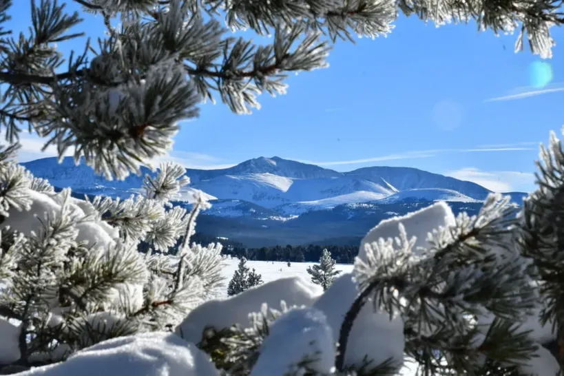 Wide open alpine meadow with fresh snow and distant mountains