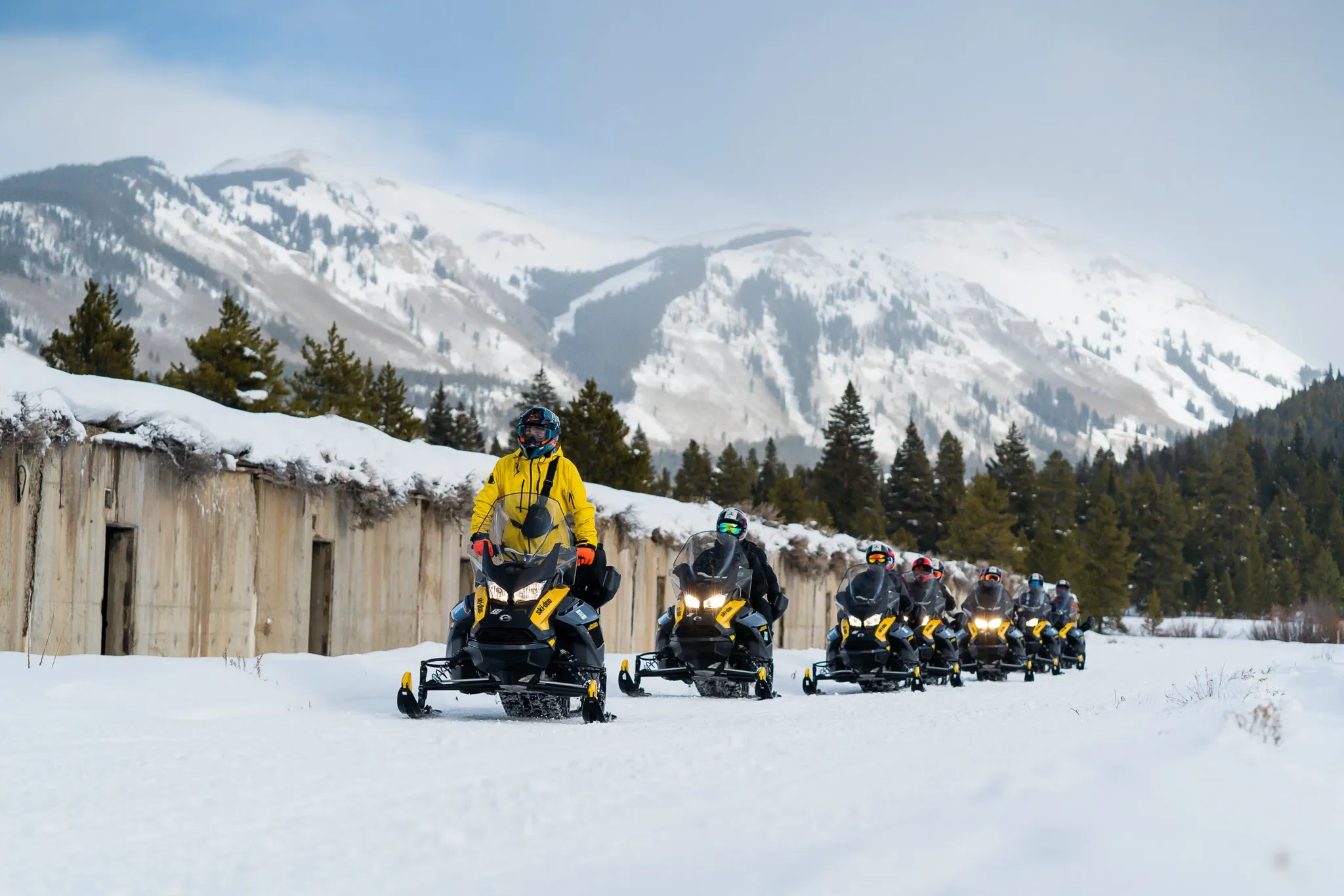 Riders on a snowy trail with alpine peaks in the background